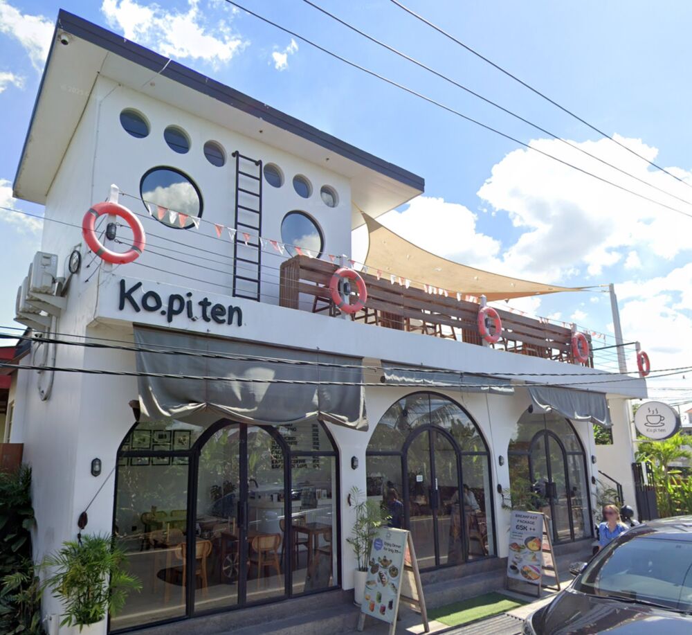 The Kopiten building from the street: white walls, round porthole windows, life rings on the roof deck and arched black-framed windows downstairs